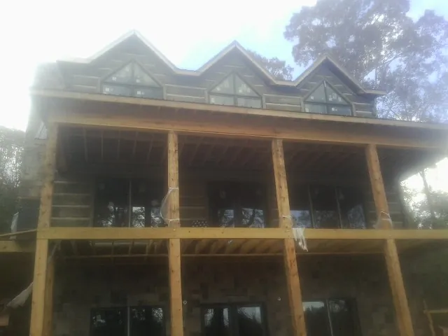 Dormers and porch framing on a large log home under construction — Roof Coating work by our crew in Markham